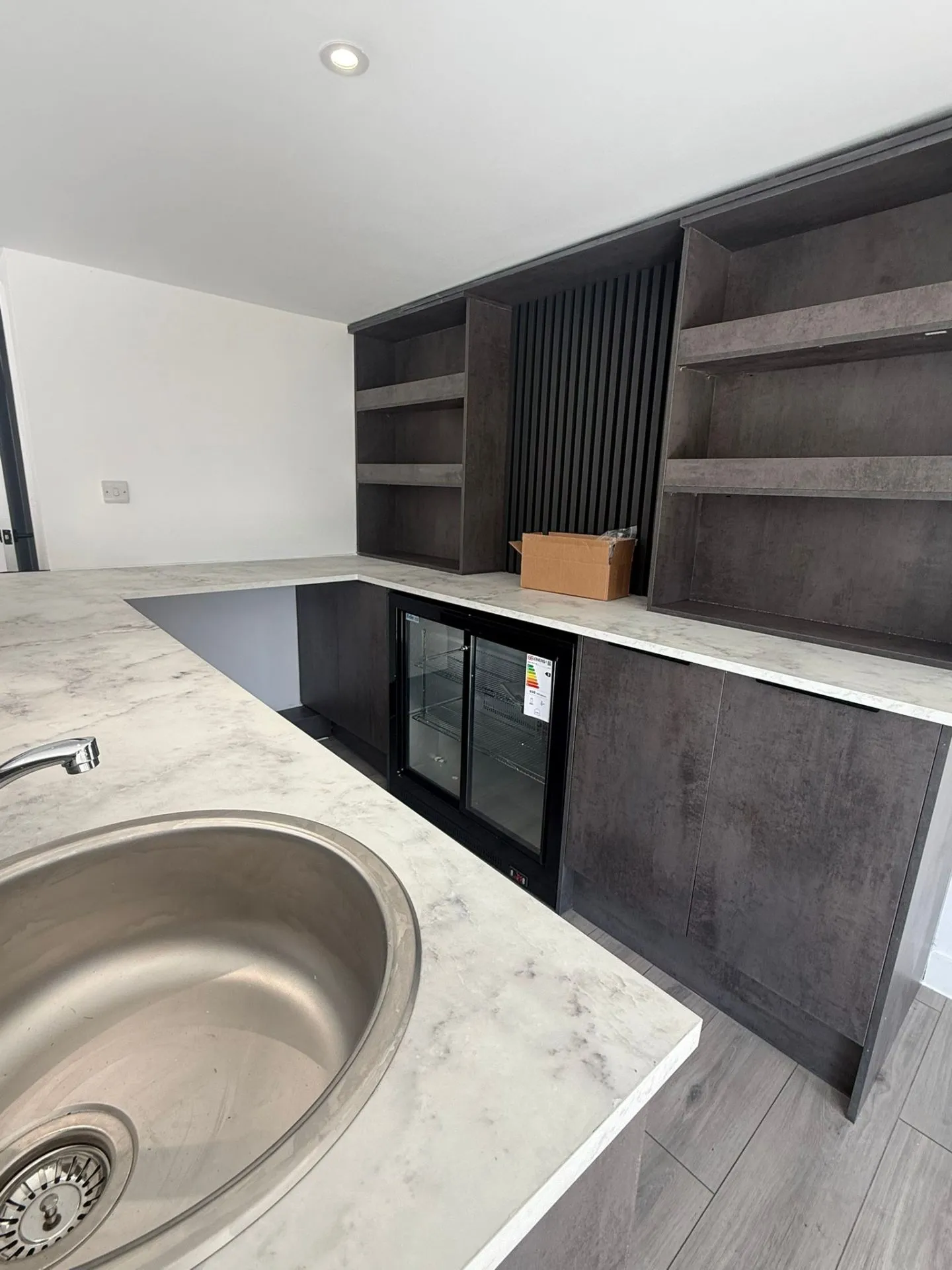 Custom bar built with Howdens Joinery — marble worktop, integrated fridge, and bar sink
