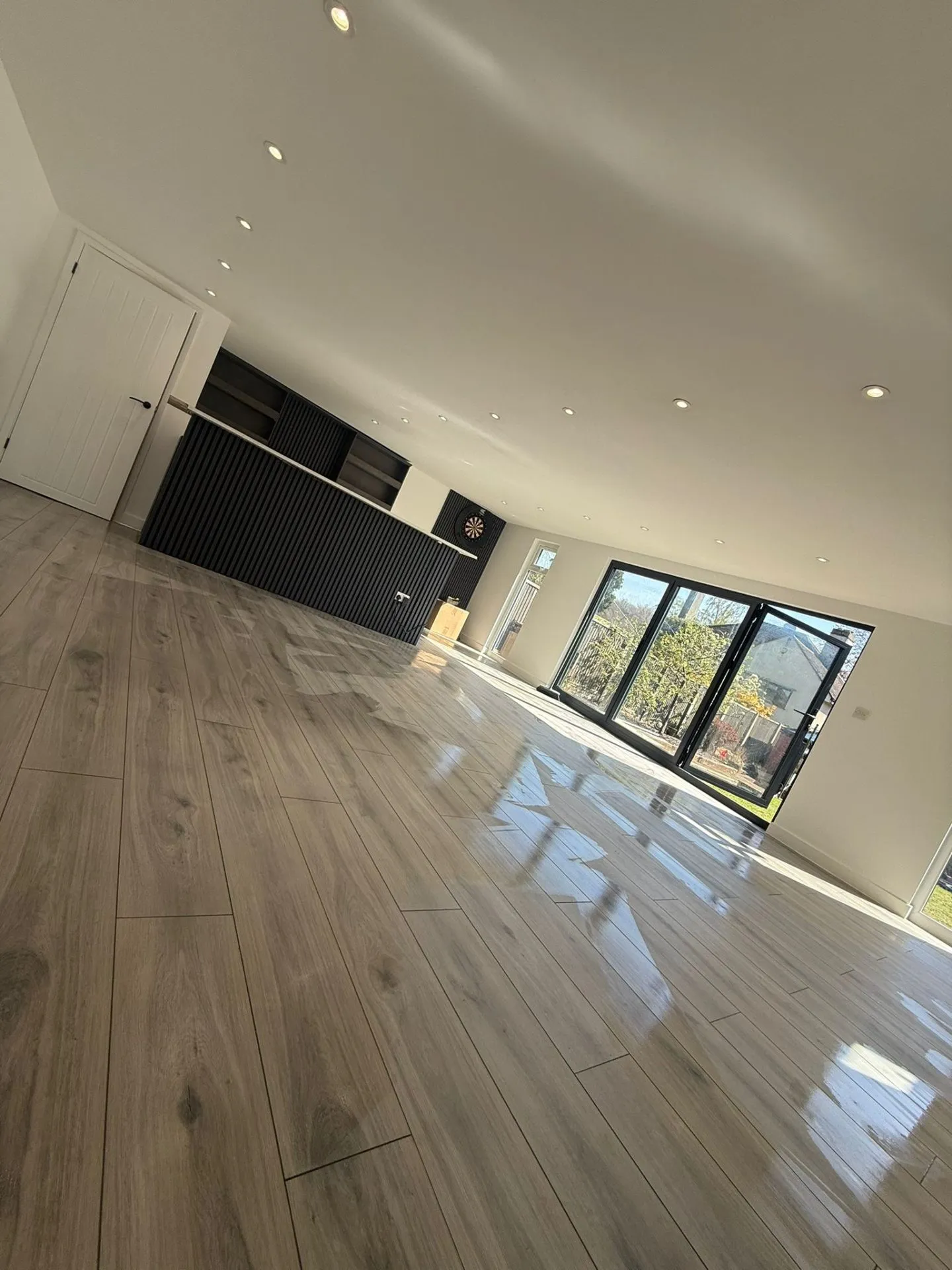 Garden room interior with custom bar, wood flooring and bifold doors